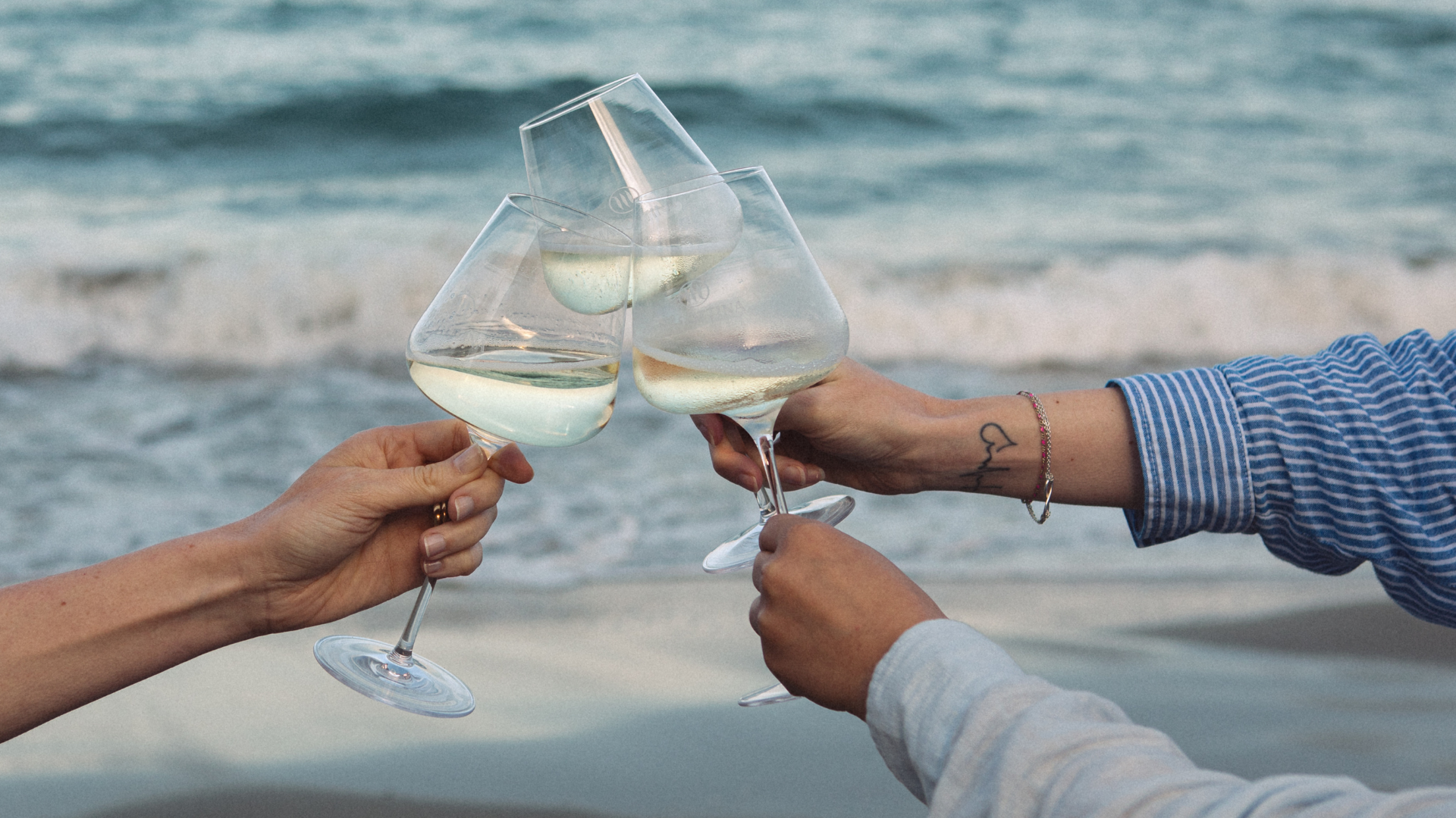 Brindisi estivo con calici Masottina sulla spiaggia e Prosecco servito alla temperatura ideale